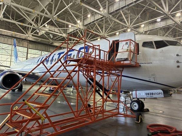 Aircraft under high-bay lighting inside a United Airlines maintenance hangar