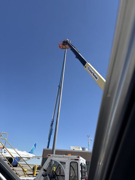 A boom lift raised to service a high-mast lighting pole on the airfield